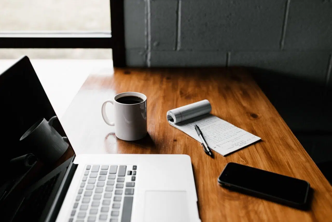 Laptop with coffee mug and notepad.