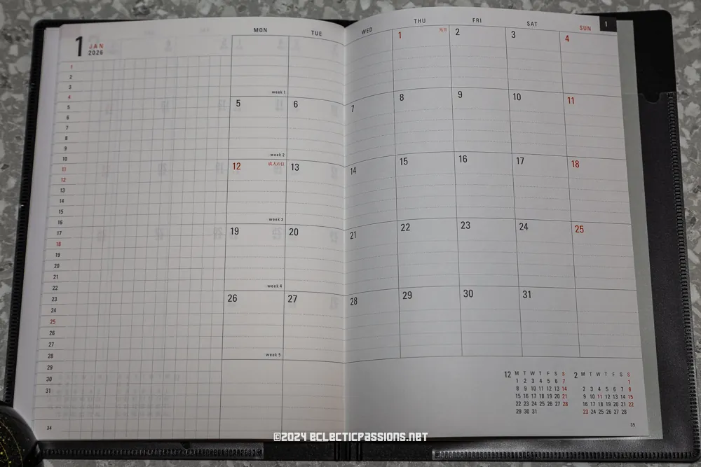 An open planner for January 2024 displayed on a gray speckled surface. The left page features a grid layout for notes, while the right page shows a calendar with dates marked in red and black.